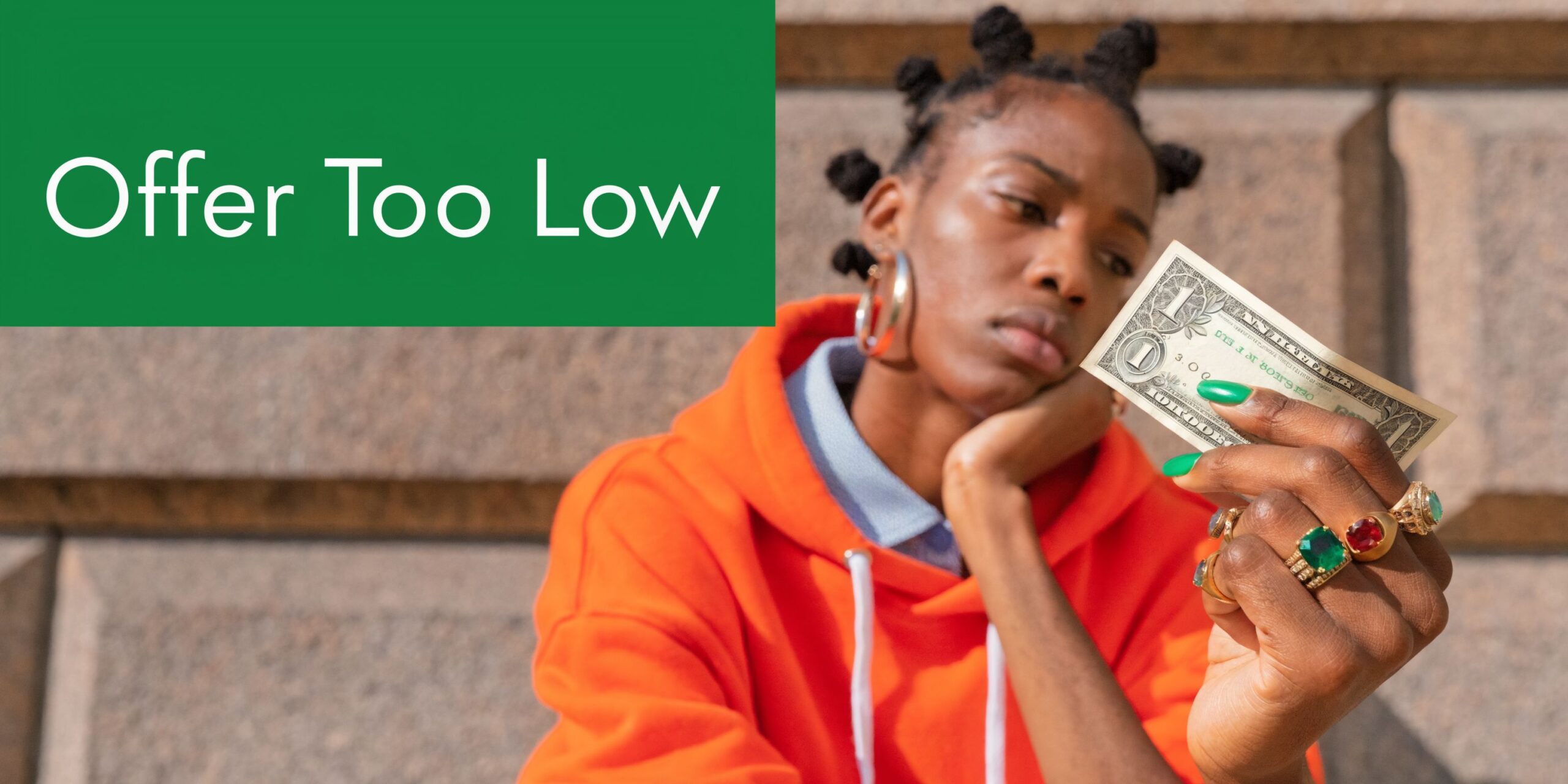 A person looking unhappy at a single dollar bill while wearing an orange hoodie.